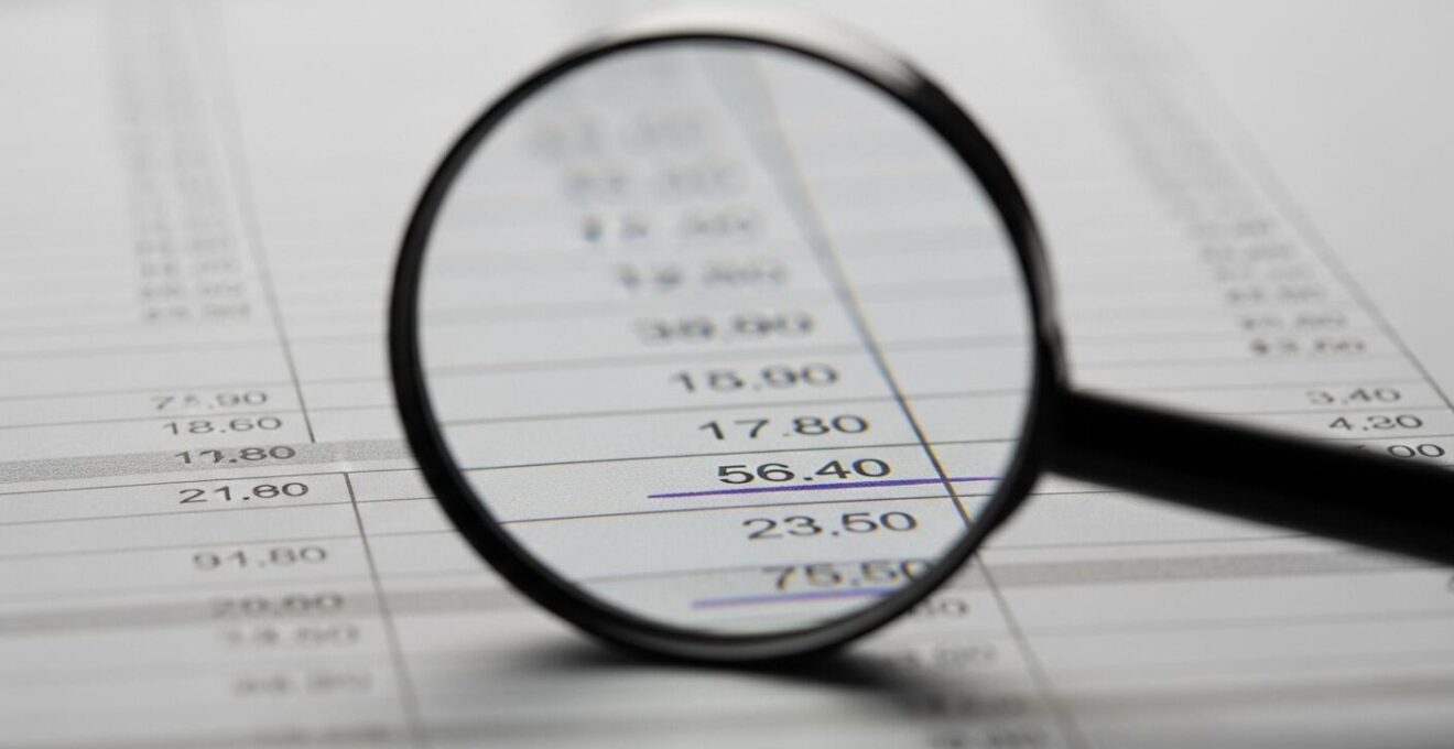 Photo macro d'une loupe révélant des détails cachés sur un bilan d'entreprise.